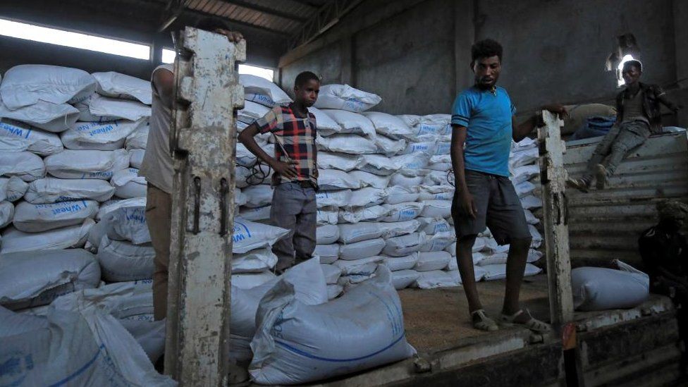 Несколько мужчин разгружают продовольственную помощь в Эфиопии