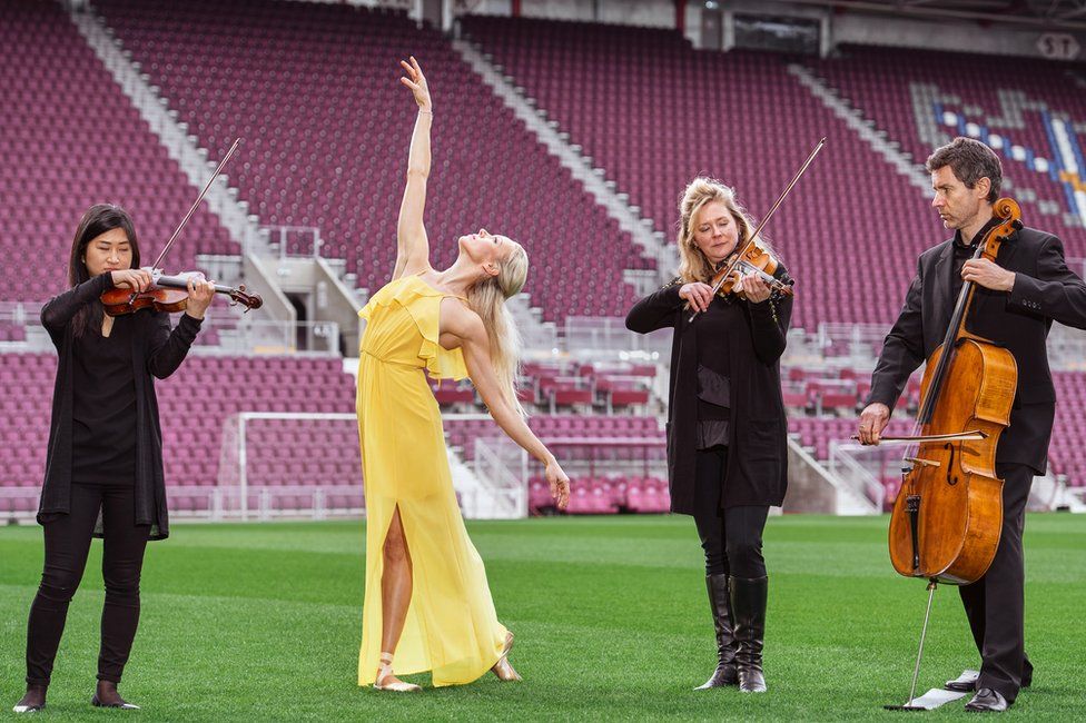 Ballet dancer Eve Mutso and musicians from the Scottish Chamber Orchestra including Amira Bedrush-McDonald (violin), Kana Kawashima (violin) and Donald Gillan (cello), celebrate the launch of the 2019 Edinburgh International Festival programme at Tynecastle Park, the venue for the Festival's Aberdeen Standard Investments Opening Event: LA Phil at Tynecastle.