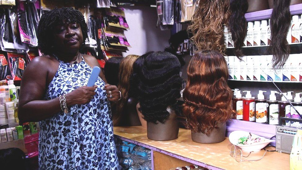 Nana Adwoa Animfu posing in front of her wig stall in Accra, Ghana.