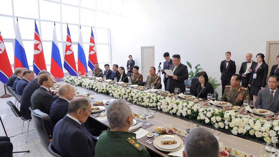 Kim Jong Un delivers a speech at a banquet table with the Russian president and officials