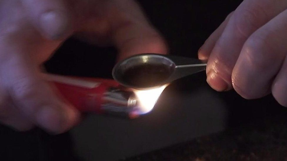 A drug addict preparing liquid heroin