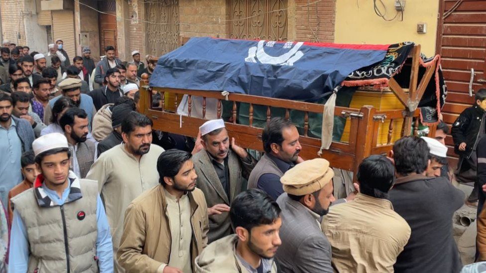 Men crowding around a coffin on a busy street