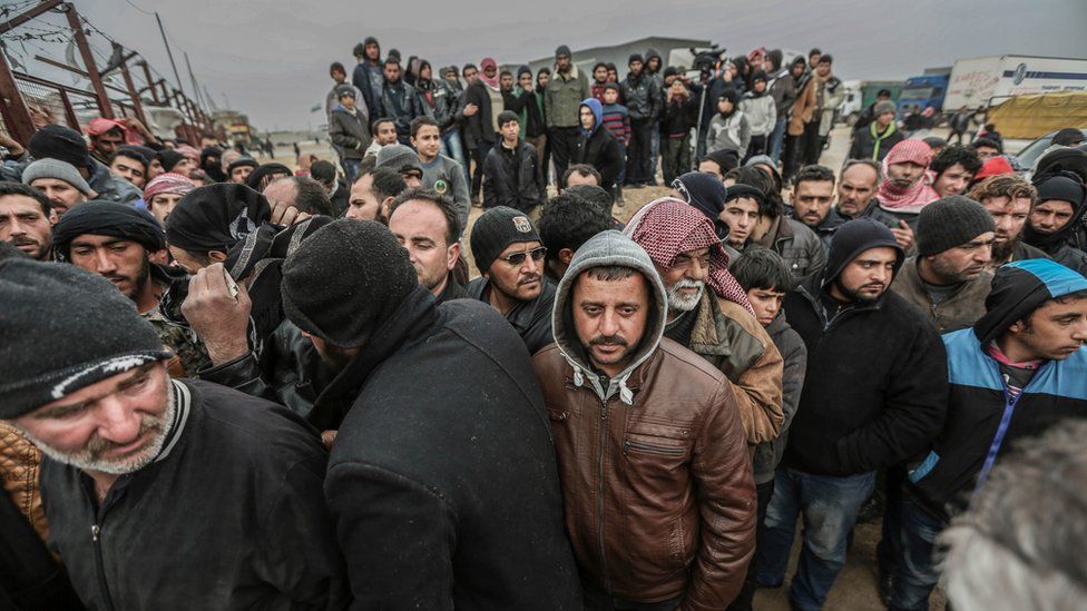 Syrians gather at the Bab al-Salam border gate with Turkey, in Syria, Saturday, Feb. 6, 2016