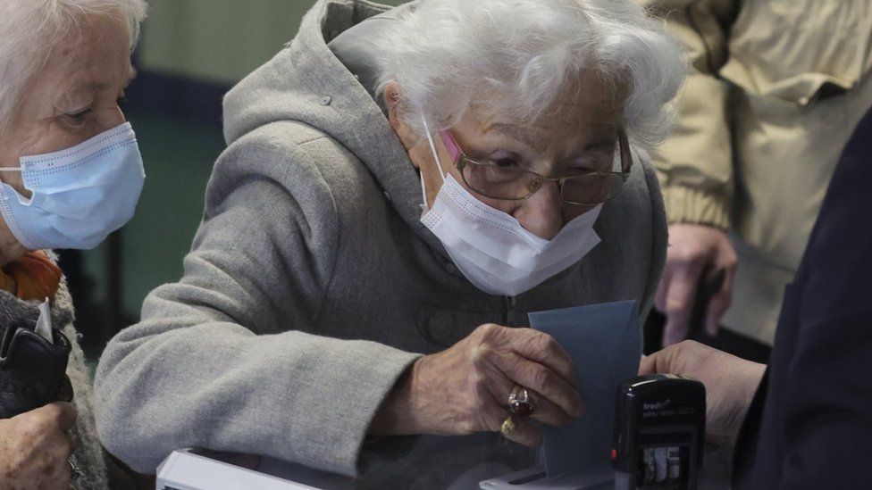 An elderly woman casts her ballot in the first round of the 2022 French presidential election at a polling station in Henin-Beaumont, France, April 10,