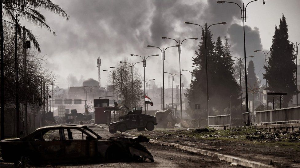 Smoke billows in the background as Iraqi forces clash with Islamic State (IS) group fighters in Mosul on March 5, 2017, during an offensive to retake the western parts of the city