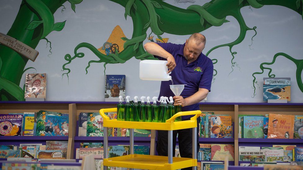Site manager Mark Lee fills bottles of hand sanitizer at Queen"s Hill Primary School in Costessey near Norwich