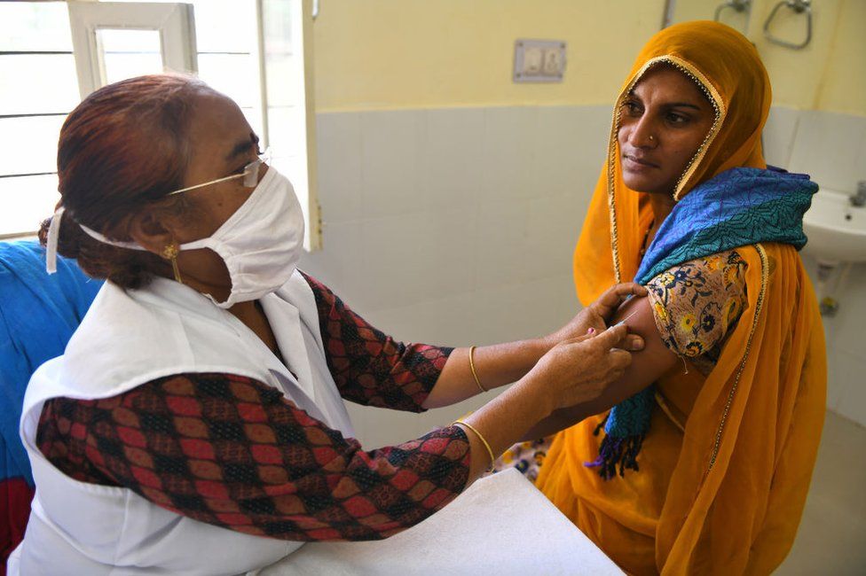Медик вводит дозу коваксина (вакцины COVID-19) сельской женщине в центре вакцинации в деревне Лири недалеко от Бивара. Раджастан