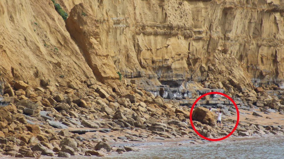 People taking photographs at the base of a collapsed cliff