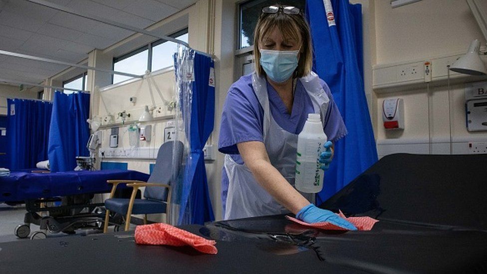A nurse sterilises a short stay bed in an NHS hospital