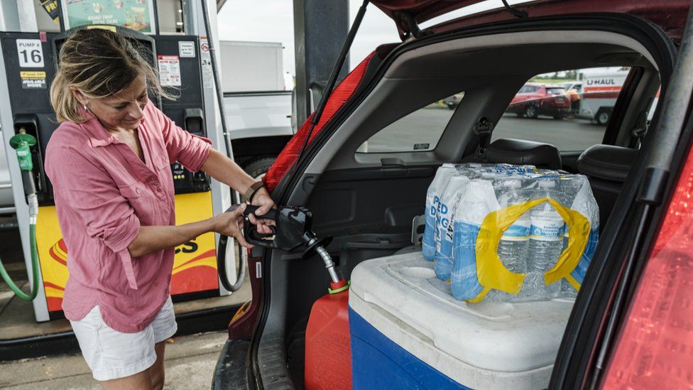 Дженнифер Тейт заправляет газовый баллон рядом с водой в бутылках и другими запасами, готовясь к прибытию урагана Ида в Пасс Кристиан, штат Миссисипи, США, 27 августа 2021 года