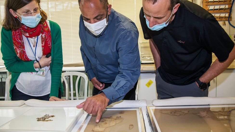 Officials look at fragments of scroll found in the Cave of Horror