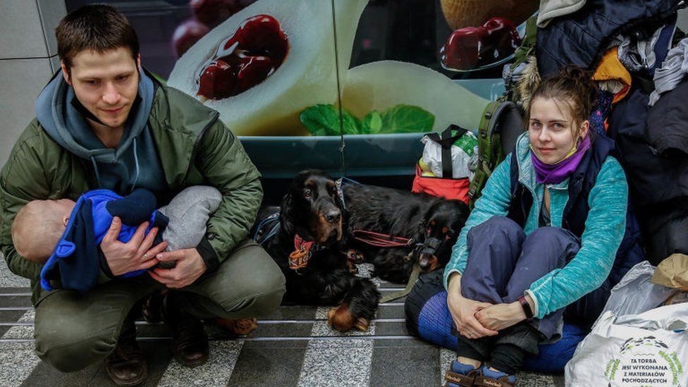 A young family with dogs rests after arriving in Poland