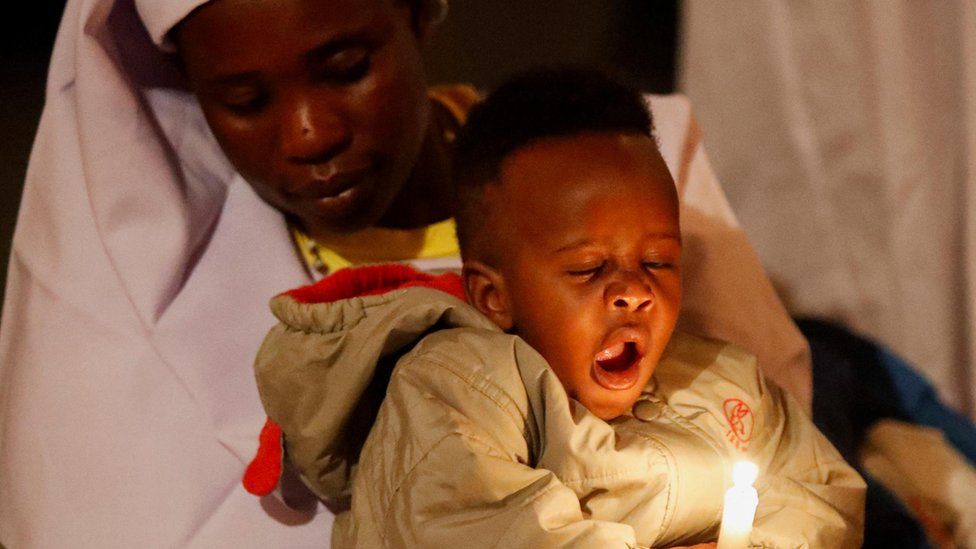A worshipper holds a child during a New Year's prayer at the St Joanes, Legio Maria of African Church Mission within Fort Jesus in Kibera district of Nairobi, Kenya - Monday 1 January 2024