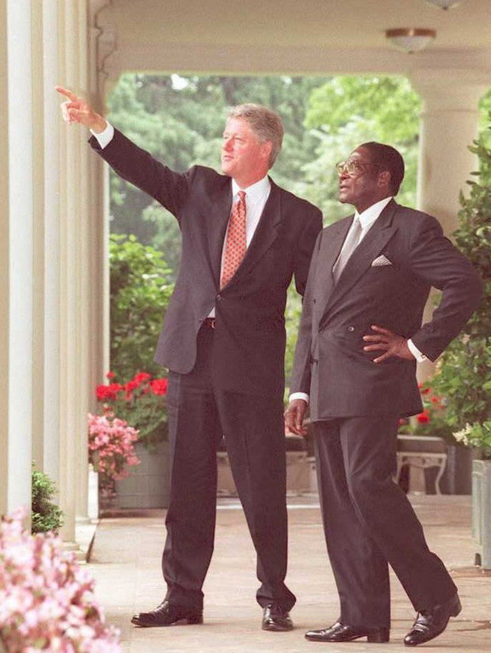 US President Bill Clinton points to items of interest on the White House grounds to President Robert Mugabe, 1995