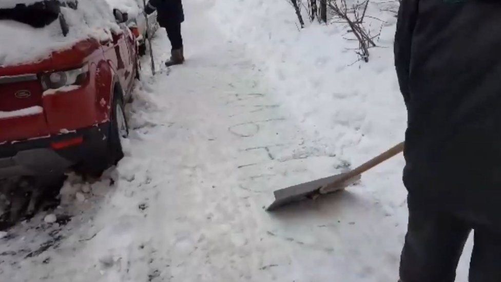 A screenshot from a video showing Moscow municipal workers scraping away the name "Navalny" from a pavement