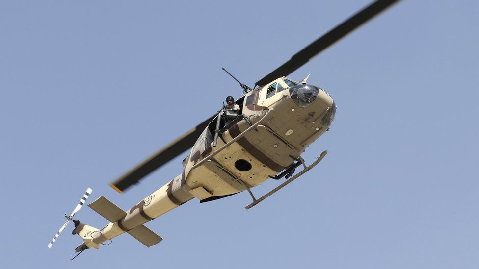 A US UH-1N military helicopter hovers over the scene after six rockets were fired near Kabul airport