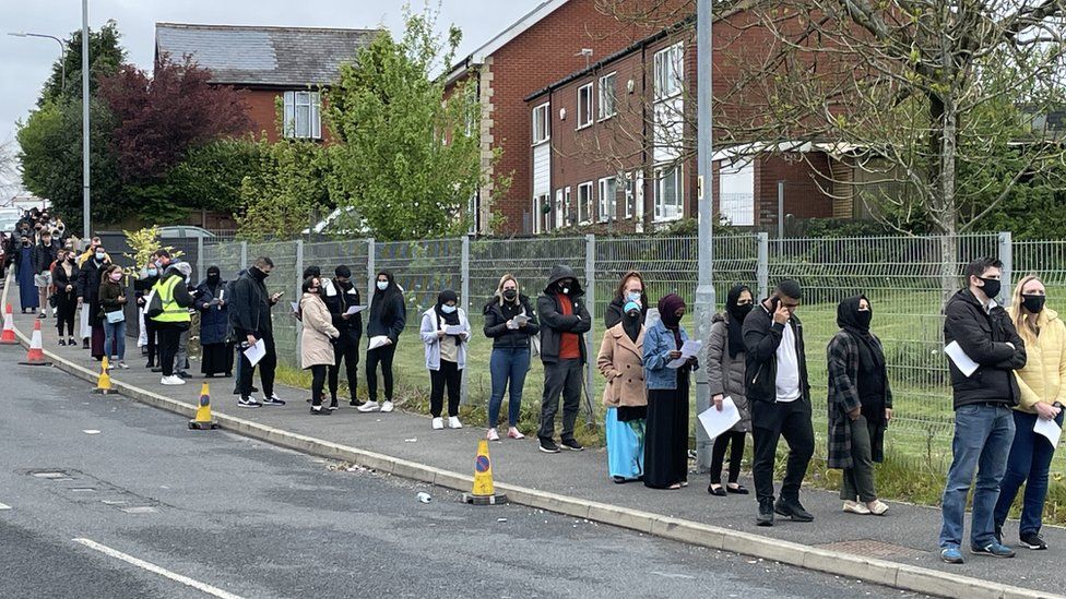 People queue for the vaccination centre at the Essa Academy in Bolton.