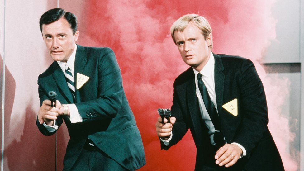 Роберт Вон и Дэвид МакКаллум направляют пистолеты в камеру в кадре из популярного фильма Телесериал «Человек из А.Н.К.Л.», около 1965 года