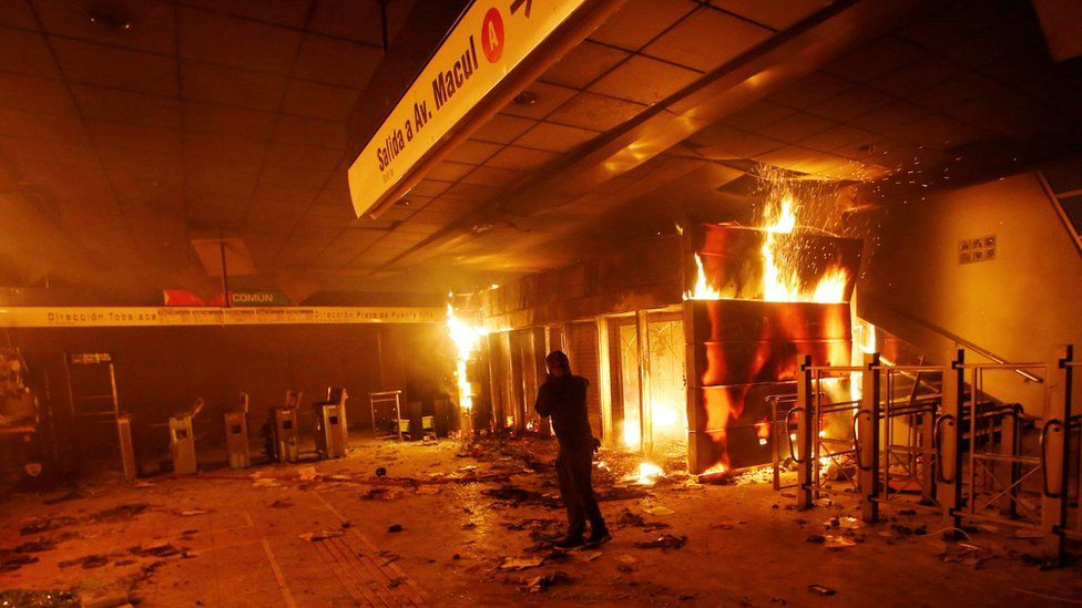 A subway ticket office is seen on fire during a protest against the increase in the subway ticket prices in Santiago