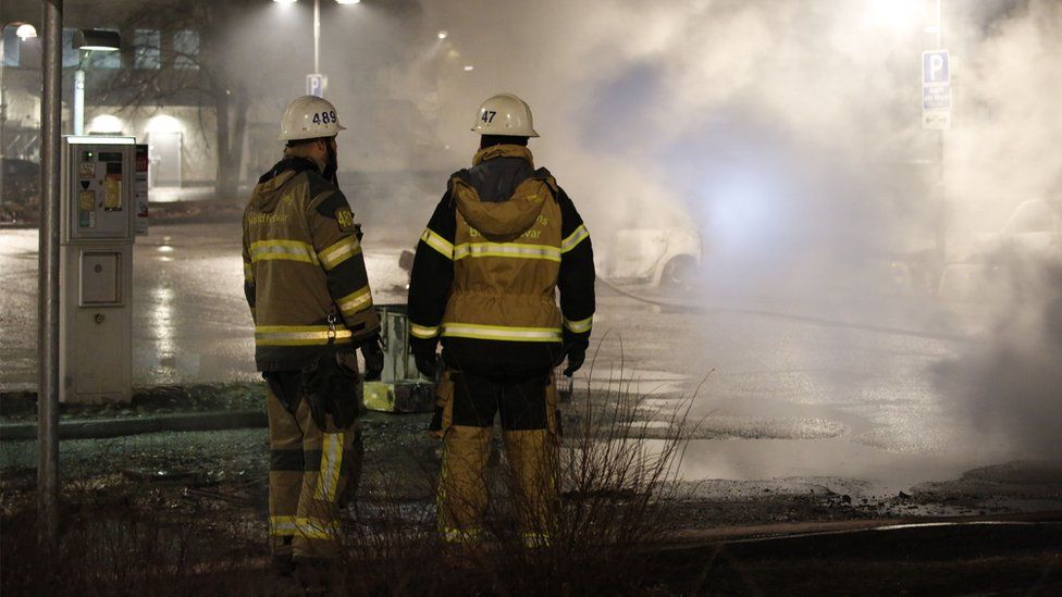 Fire fighters look at smoke in the suburb Rinkeby, outside Stockholm, on 20 February 2017
