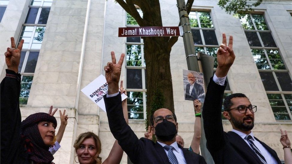 Активисты ставят V-знаки перед дорожным знаком Джамала Хашогги Уэй в Вашингтоне, округ Колумбия (15/06/22)
