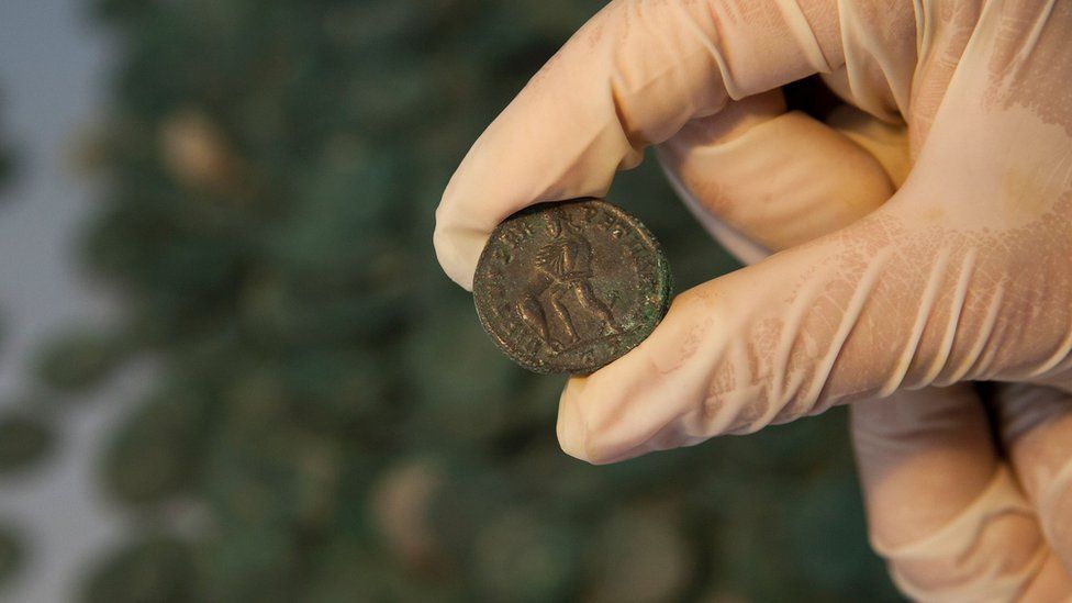 A Roman bronze coin is held up