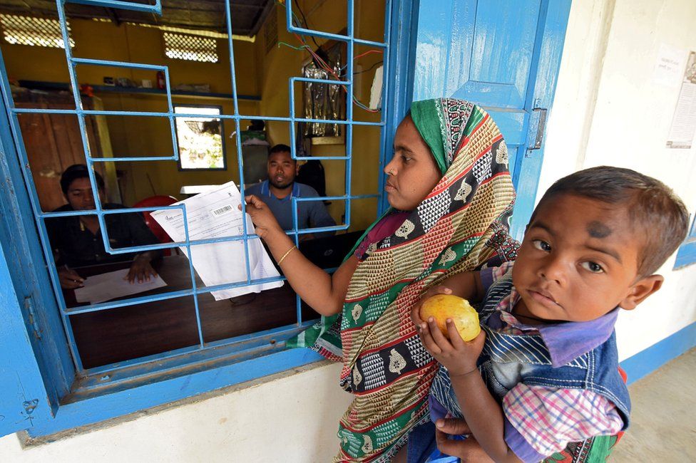 A woman carrying her son arrives to check her name on the draft list of the National Register of Citizens (NRC) centre in Chandamari, Assam.