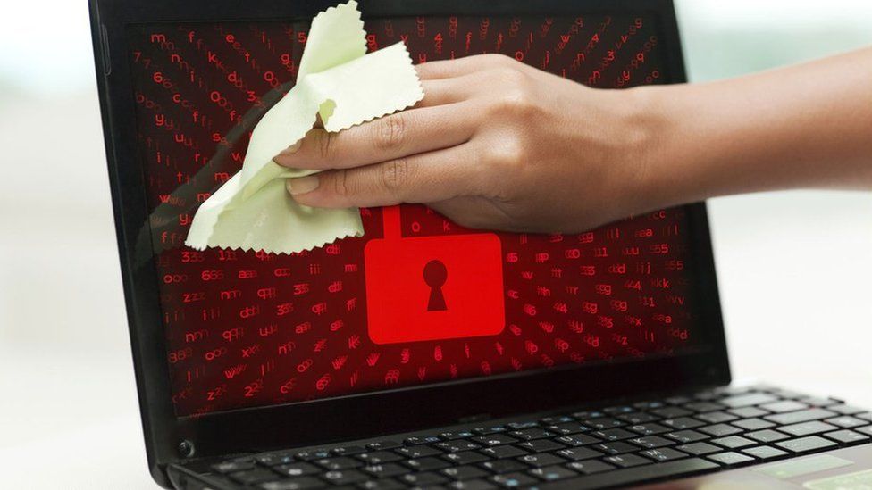 A composite image shows someone cleaning a laptop screen while a red padlock image is displayed on screen