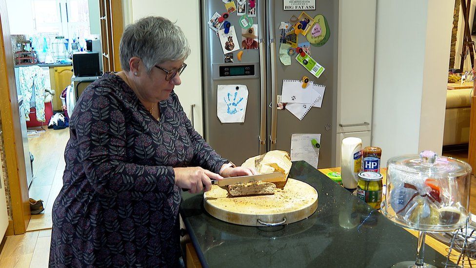 Линетт Пети режет хлеб на кухне