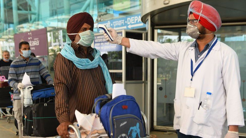 A health worker checks the body temperature of a passenger