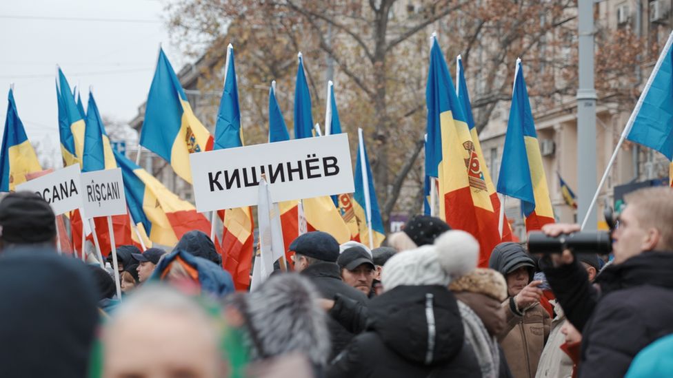 Moldovans protesting against the President hold up flags and signs