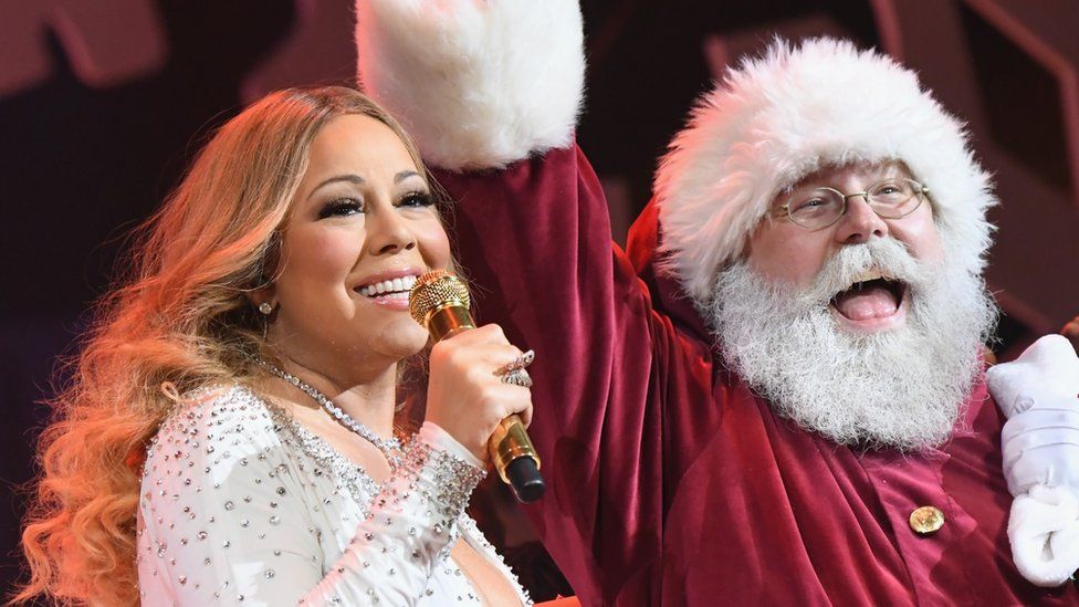 Mariah Carey with a person dressed as Santa Claus