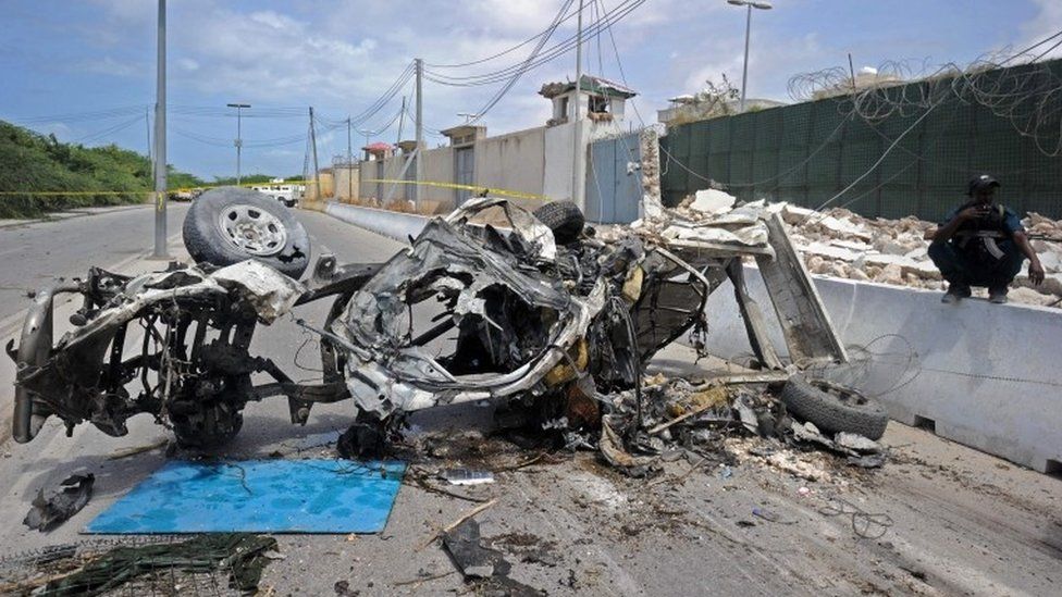 Somali soldiers stands on guard next to the wreckage of a car bomb outside the UN"s office in Mogadishu on July 26, 2016.