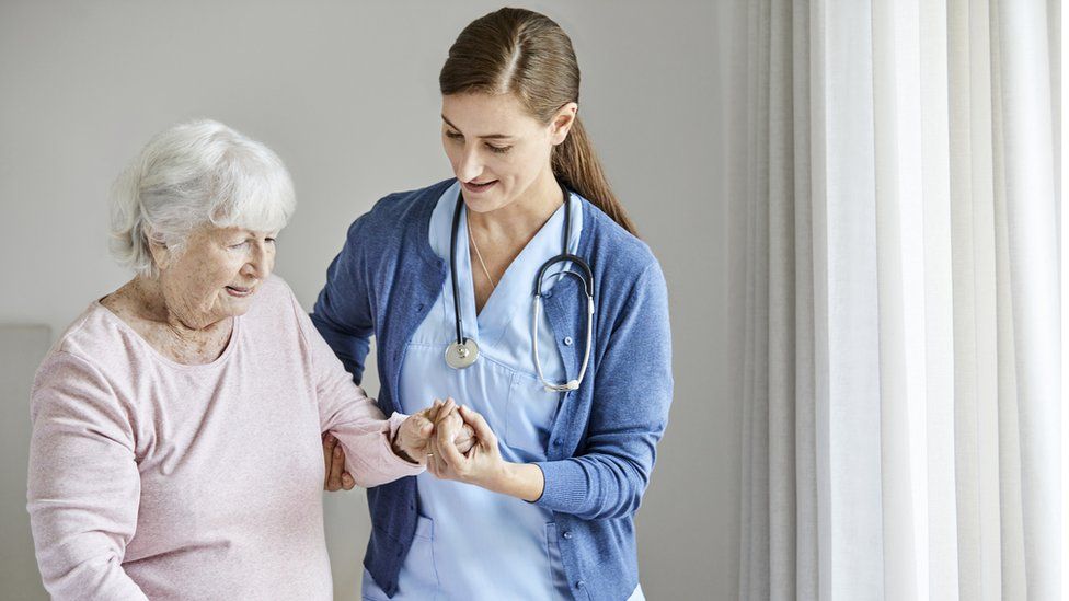 Eine Krankenschwester, die einer älteren Frau hilft