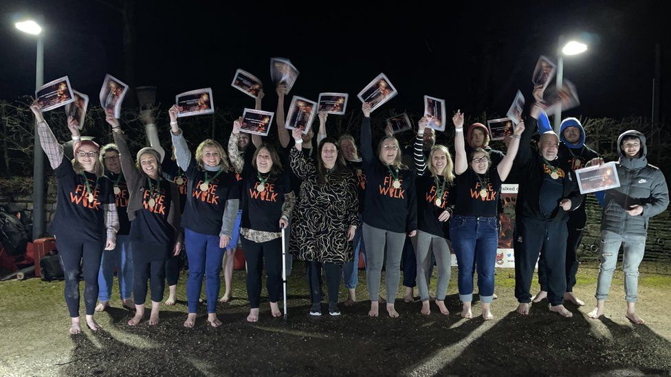 A group of people holding their firewalk certificates above their heads
