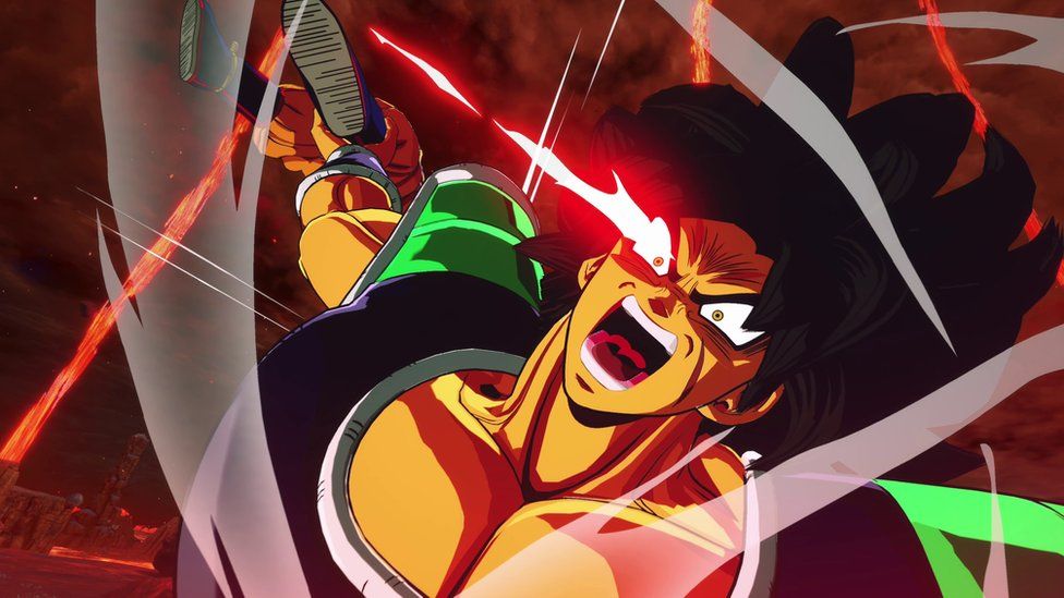 A character from Dragon Ball. The character has exaggerated spiky black hair and a muscly physique. The character has an angry expression, eyebrows furrowed and mouth open wide with a red laser seeming to come from his right eye. He wears a black armour-style top with green shoulder pads. He holds another character by the ankle behind him as if to throw him. The scene is red with lasers and smoke intersecting it.