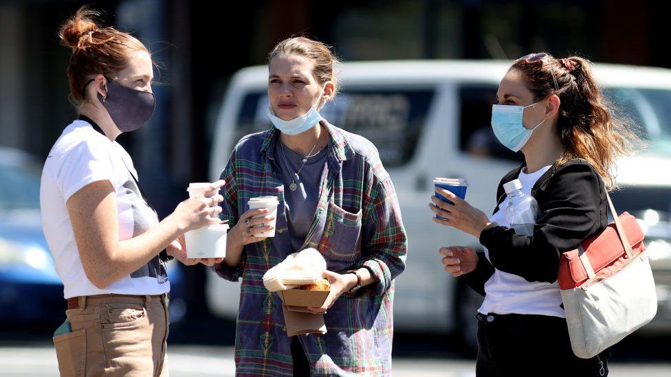 Women wear face coverings as they chat over coffee in Aukland, New Zealand