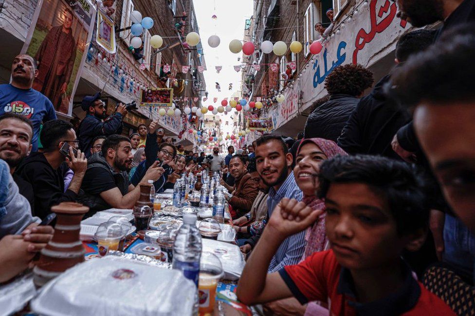 People line long tables for an iftar feast in a residential neighbourhood.
