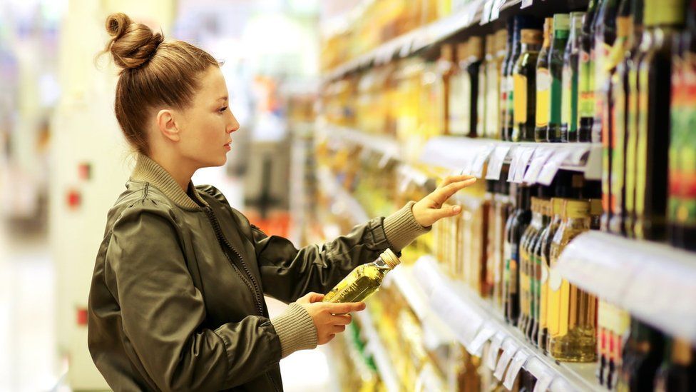 Woman looking at cooking oil on supermarket shelves