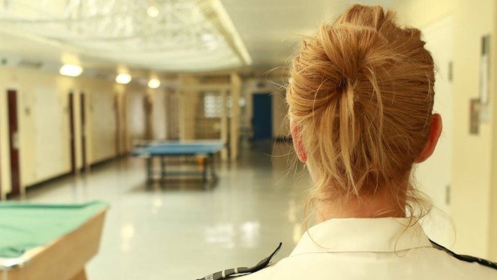 An anonymous female prison officer patrolling a prison wing
