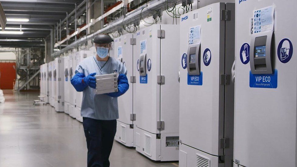 A worker passes a line of freezers holding coronavirus disease (COVID-19) vaccine candidate BNT162b2 at a Pfizer facility in Puurs, Belgium in an undated photograph.