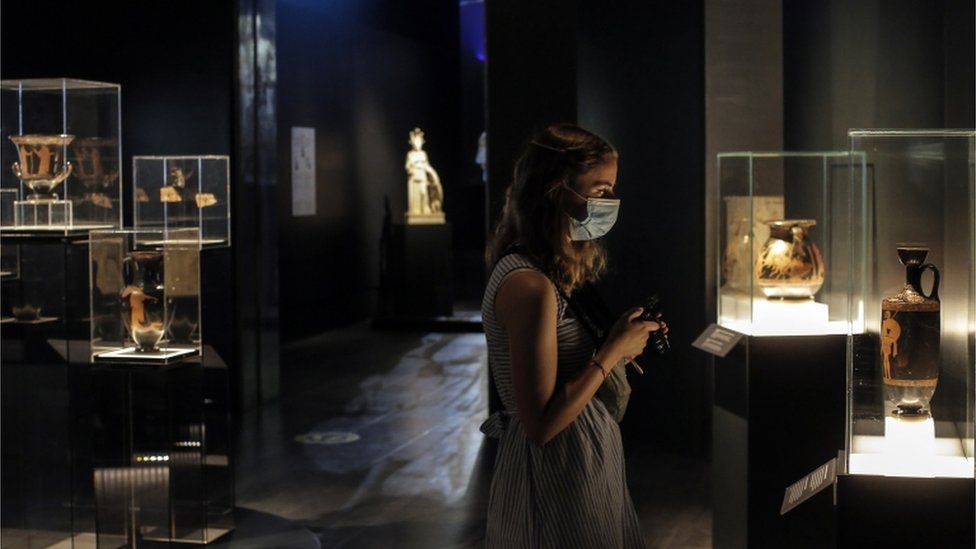 A visitor wearing a protective mask looks on Ancient Greek artefacts exhibited at National Archaeological Museum in Athens, Greece, 14 May 2021