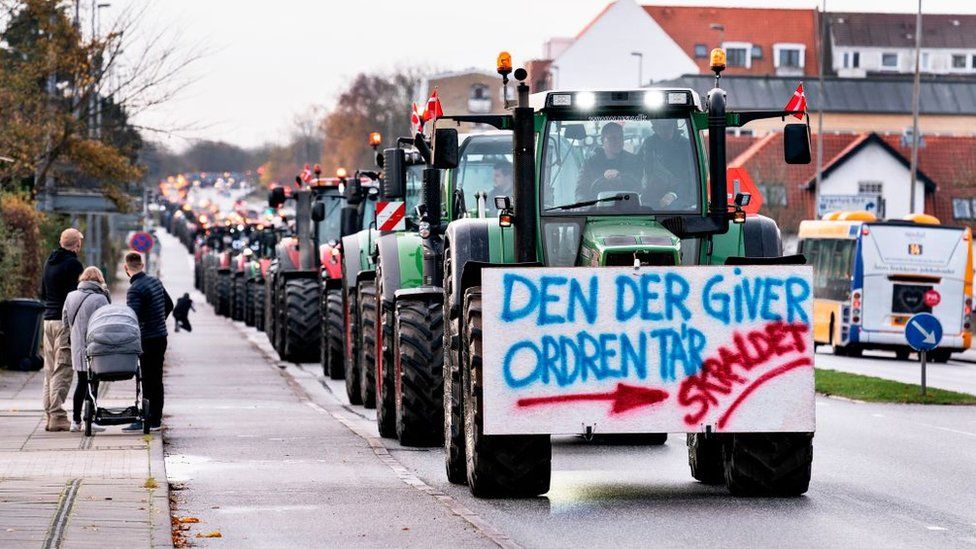 A farmer on a tractor with a placard reading 'The one who gives the order - Garbage' protests on November 14, 2020 in Aalborg, northwestern Denmark, during a rally against the Danish governments' order to cull all mink in the country.