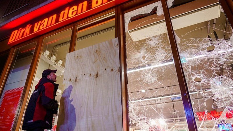 A worker boards up broken windows on a branch of supermarket chain Dirk van den Broek in Rotterdam