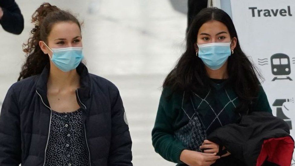 Commuters, some wearing face coverings to help prevent the spread of coronavirus, walk through Waterloo train station in central London.