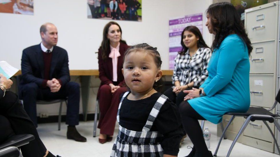 Child approaches camera as the royal couple visit a charity in Chelsea, Massachusetts