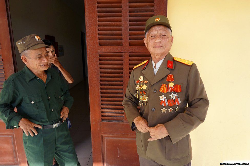Pham Xuan Do (right), 77, buttoning his original uniform in the presence of retired captain Le Quang Kieu (left), 68, and retired lieutenant sergeant Hoang Ding Li (center), 73, at Friendship Village
