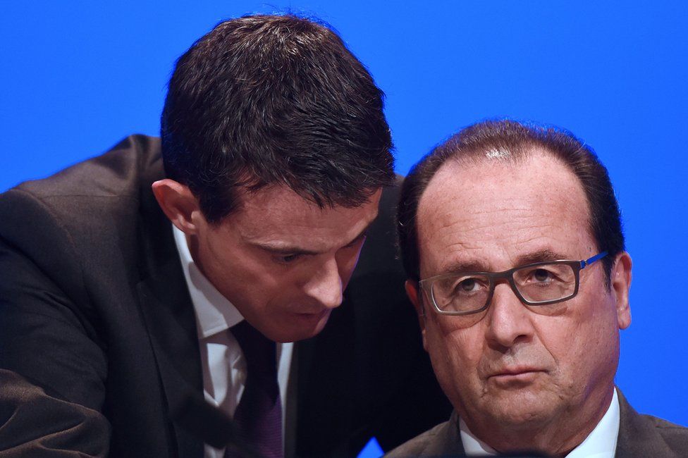 French Prime Minister Manuel Valls (L) speaking to French President Francois Hollande before he delivers a speech during a meeting of French mayors in Paris, 18 November