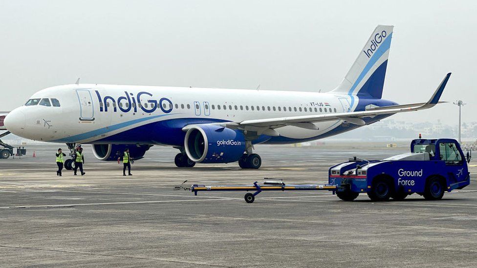 Ground staff walk past an Indigo airlines aircraft taxiing in the apron at the Netaji Subhash Chandra Bose International airport in Kolkata on February 1, 2024. (Photo by Indranil Mukherjee / AFP) (Photo by INDRANIL MUKHERJEE/AFP via Getty Images)