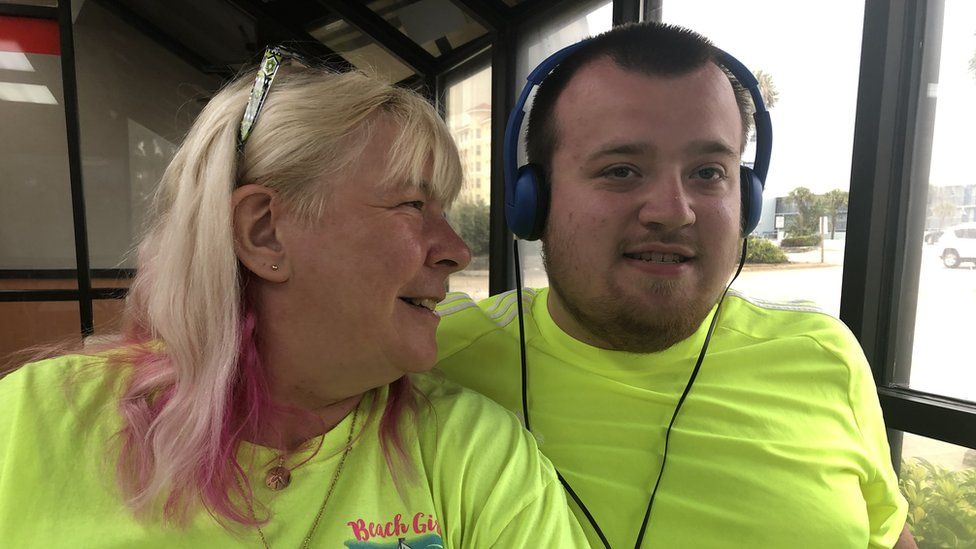 Woman with long blond hair and young man with short brown hair wearing headphones
